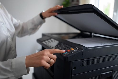A woman uses a photocopier to copy a document she holds