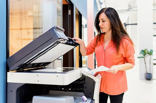 A woman uses a photocopier to copy a document she holds